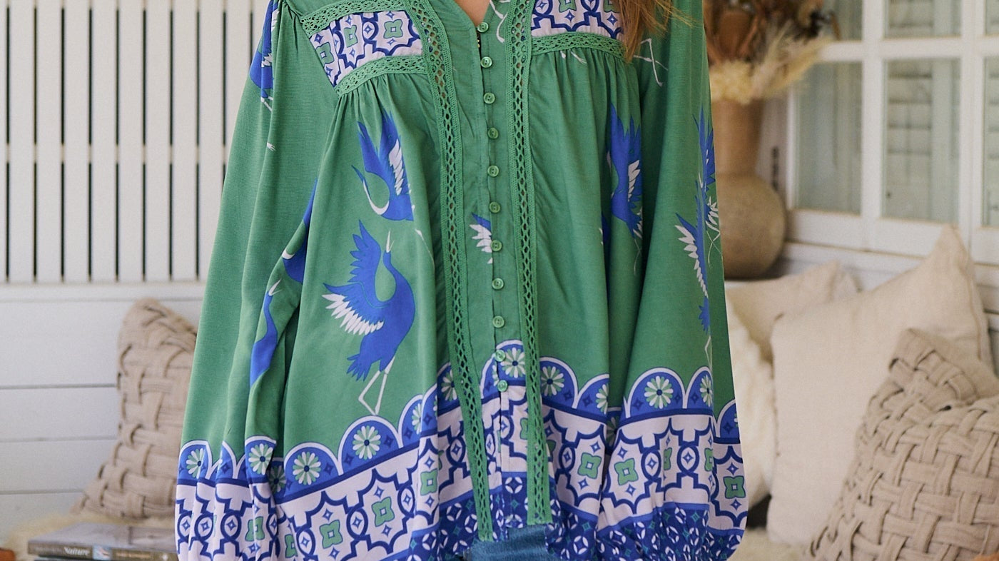 Model wearing the Bluebird Bee Boho Blouse - jade green oversized boho top with lace detailing, long billowed sleeves, and bluebird print."