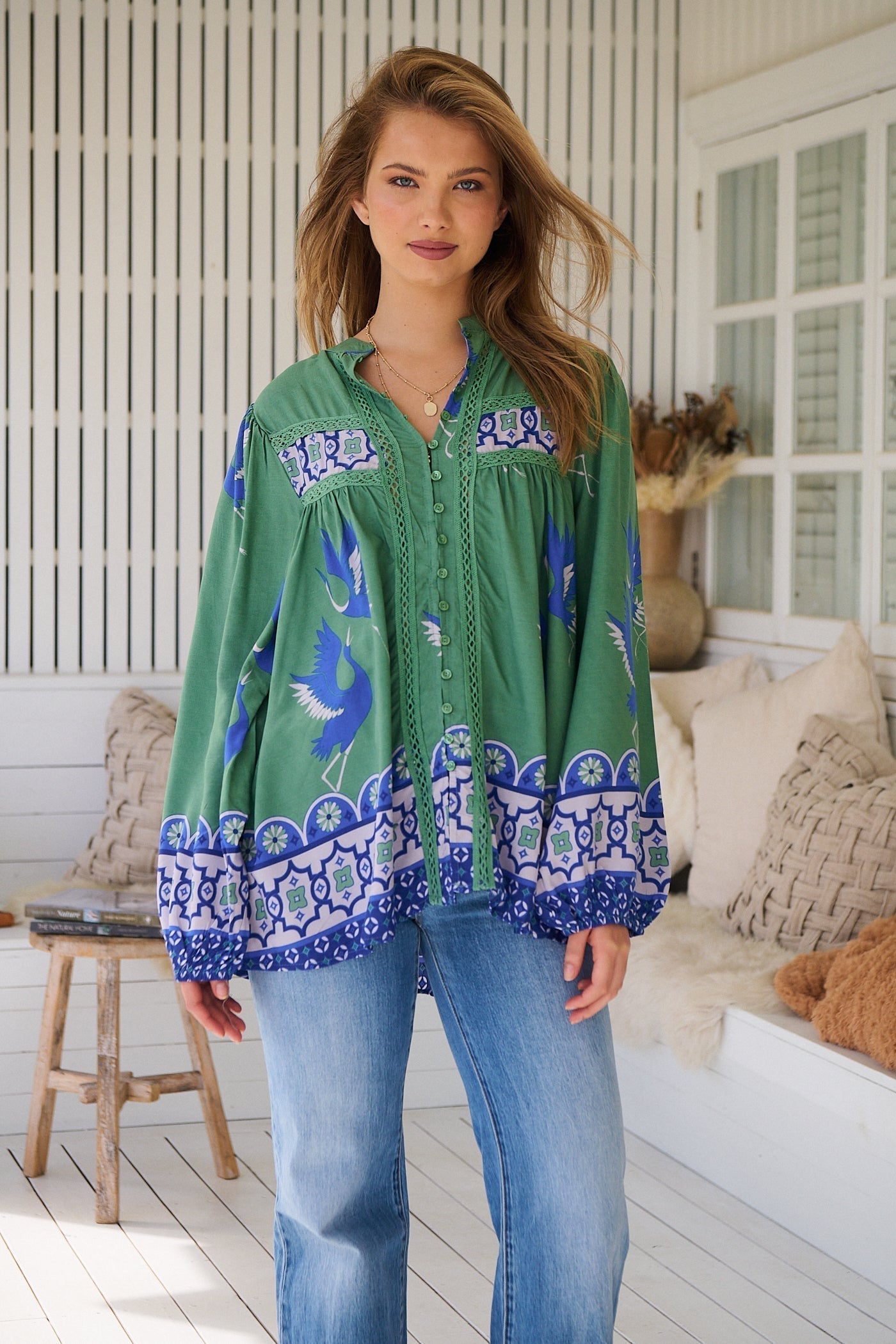 Model wearing the Bluebird Bee Boho Blouse - jade green oversized boho top with lace detailing, long billowed sleeves, and bluebird print."