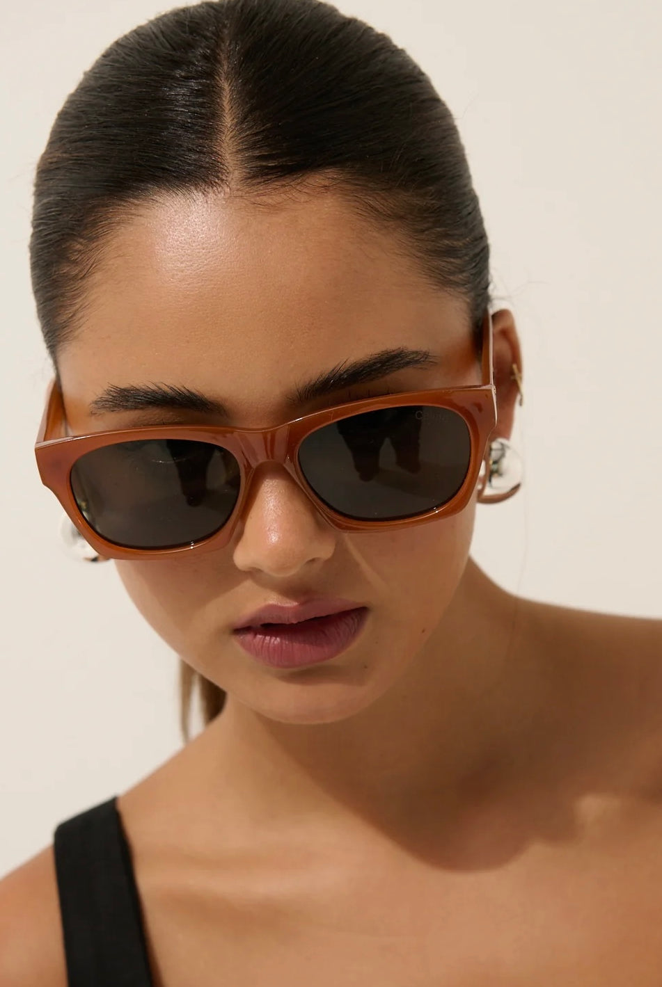 Woman in brown square boho sunglasses with slick hair and dark lip— vintage-inspired summer style Australia.