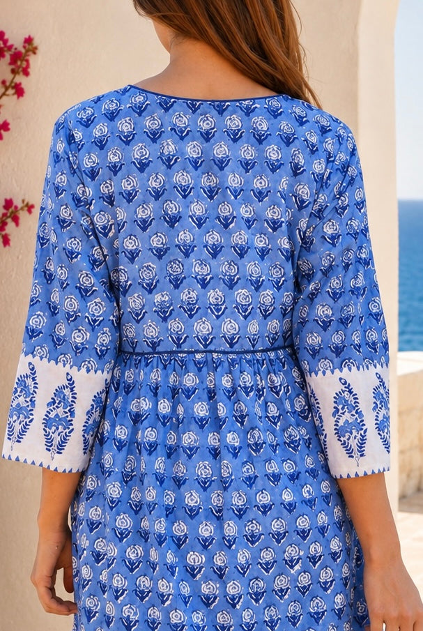 A woman wearing a blue and white printed cotton kurta, shown from the back. The dress features a delicate blue floral block print on a white base, with white cuffs decorated with block print border.