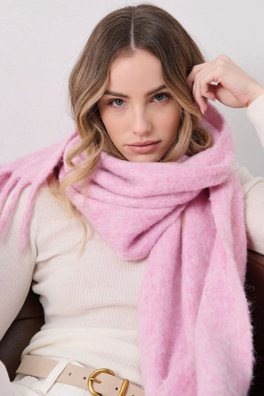 Woman in a soft blush pink boho scarf with tassels styled over a knit jumper - Rosabella scarf Australia.