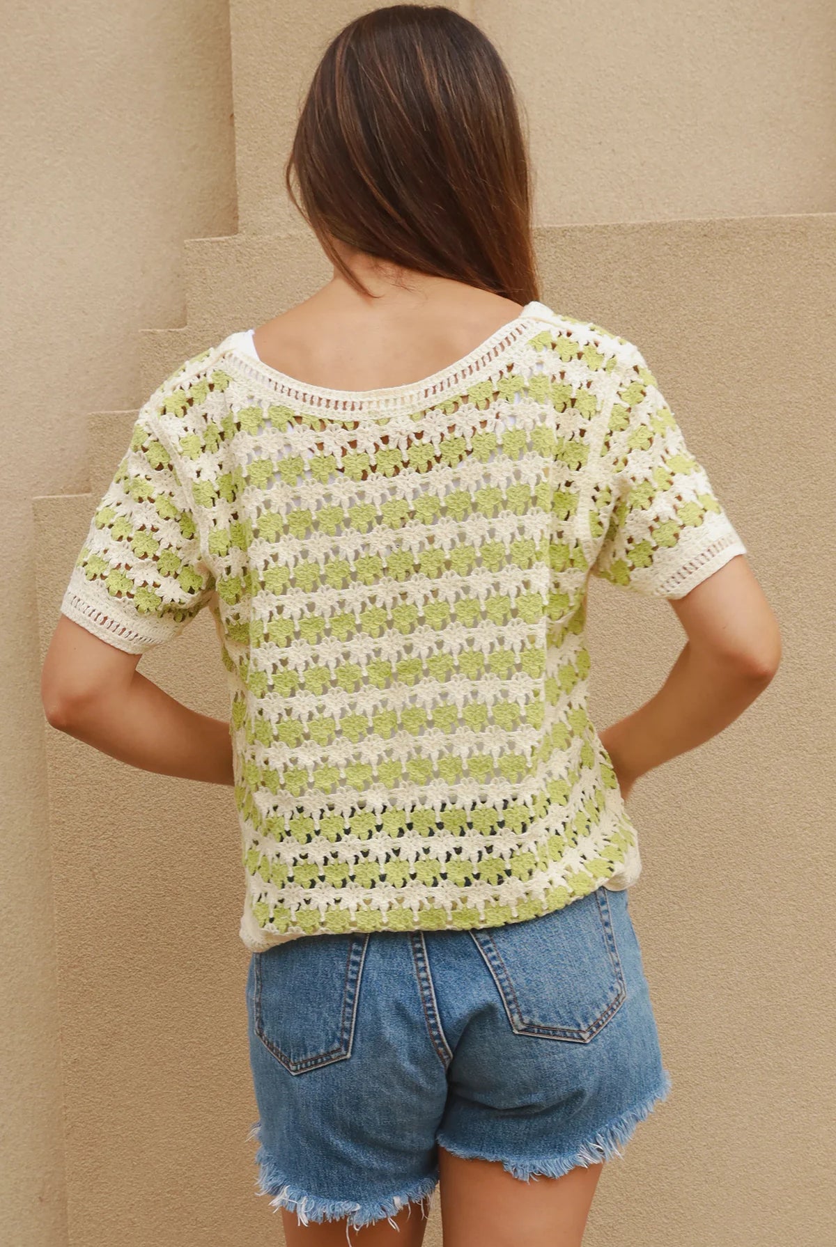 Woman wearing lime and cream crochet cotton top with vintage pattern and denim shorts - boho summer fashion Australia.