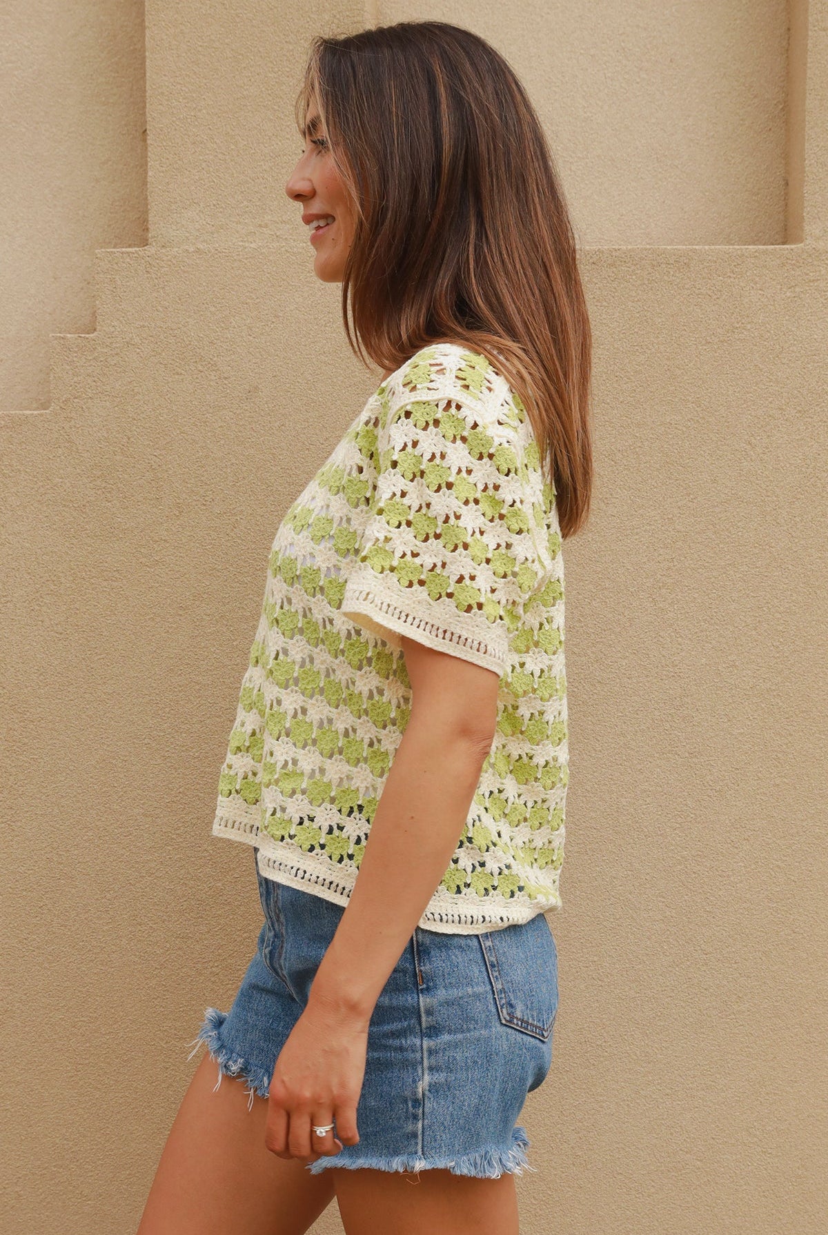 Woman wearing lime and cream crochet cotton top with vintage pattern and denim shorts - boho summer fashion Australia.