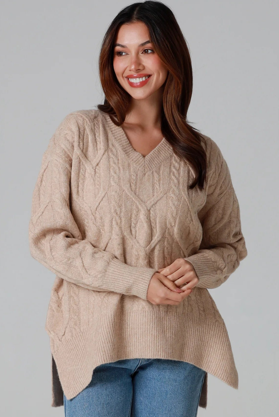 Woman wearing a biscotti colour wool blend cable knit jumper with relaxed fit and v-neckline - Caldra Knit Jumper Australia.