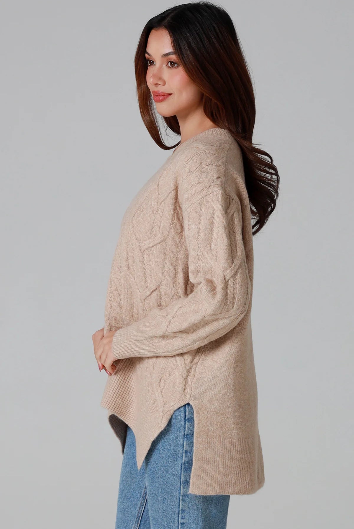 Woman wearing a biscotti colour wool blend cable knit jumper with relaxed fit and v-neckline - Caldra Knit Jumper Australia.