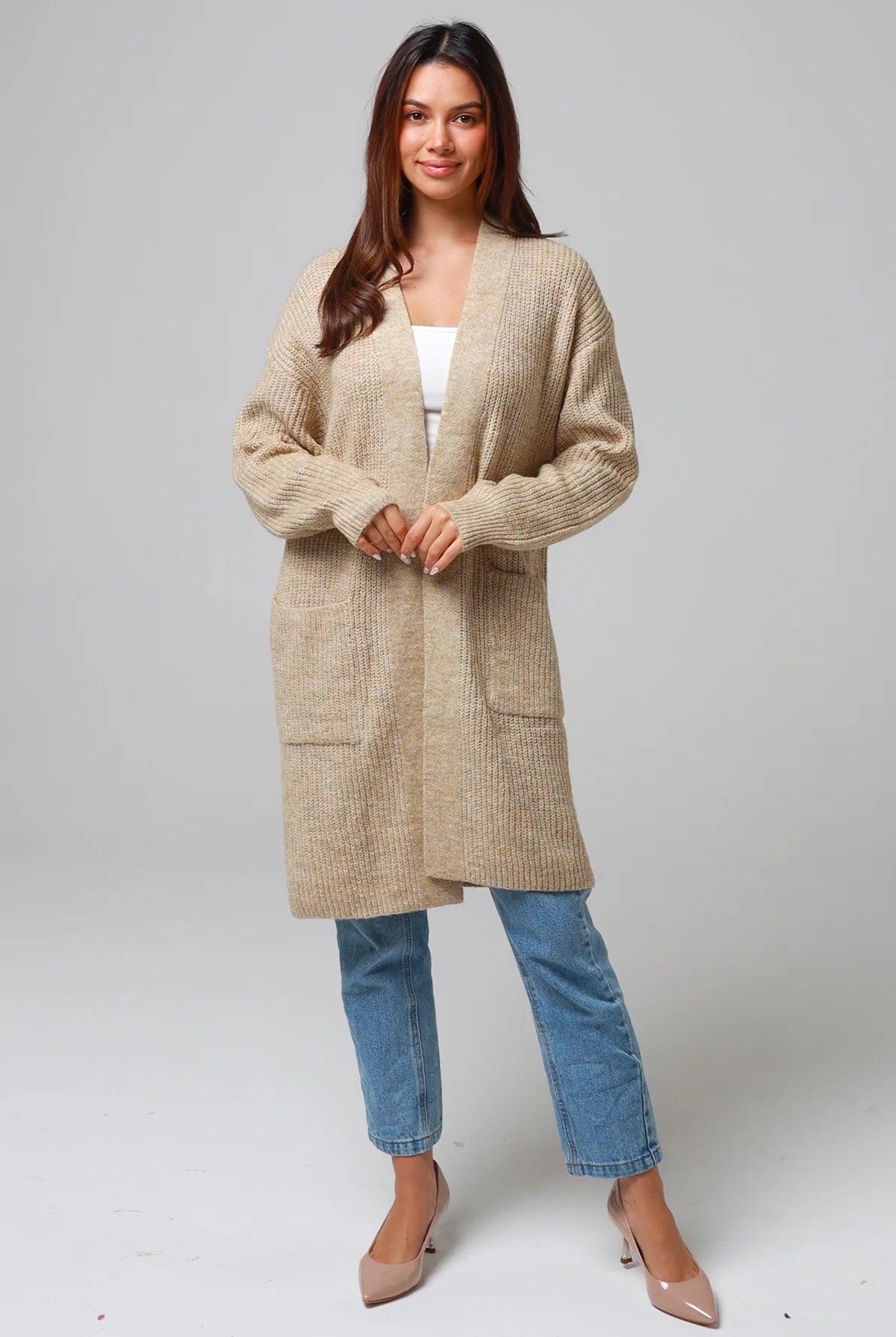 Woman wearing a beige longline knit cardigan with front pockets and jeans - neutral boho knitwear Australia.