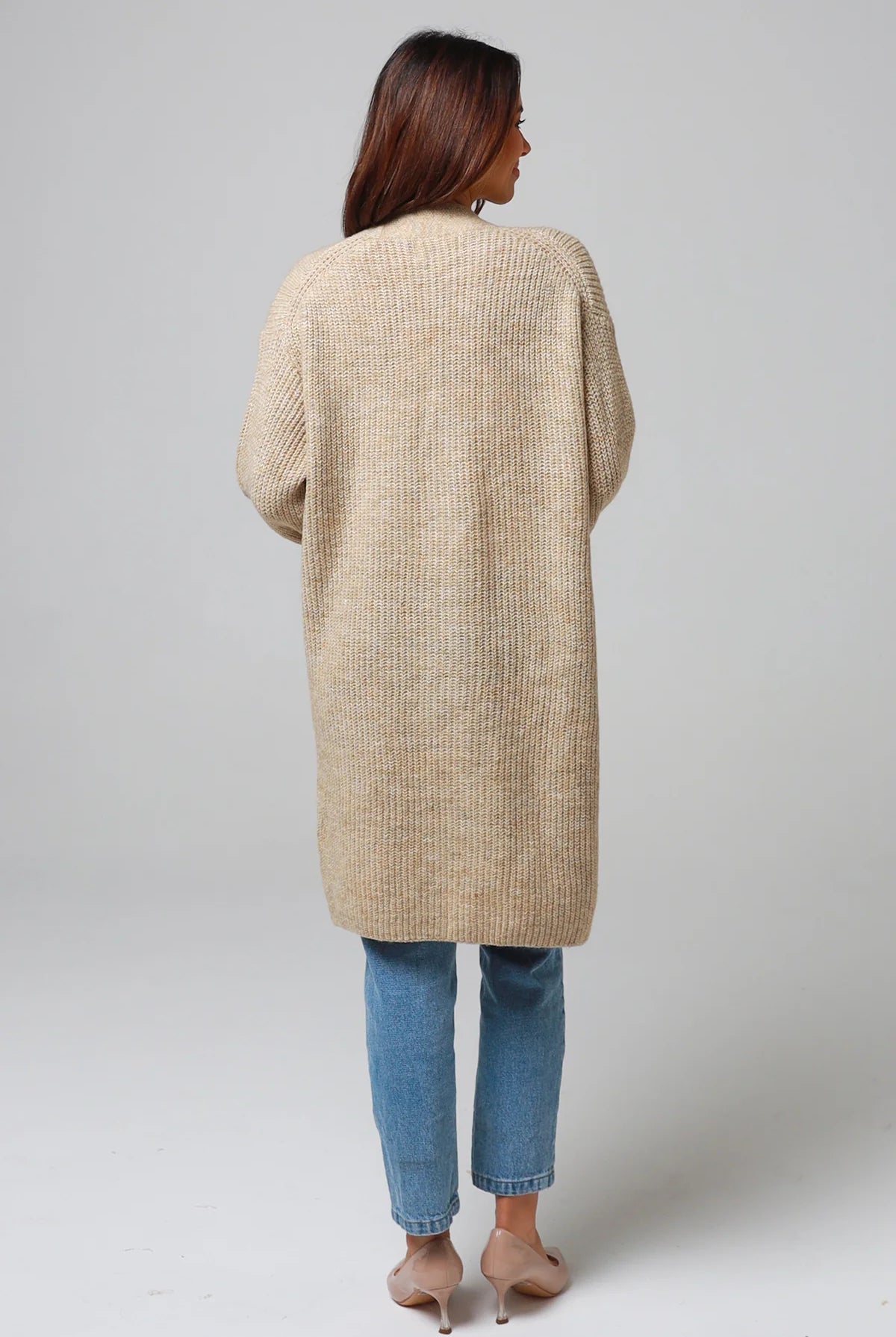 Woman wearing a beige longline knit cardigan with front pockets and jeans - neutral boho knitwear Australia.