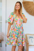 Woman in multicolour boho tiered mini dress with v-neckline, puff sleeves, shirred waist and oversized hemline - Australian bohemian style