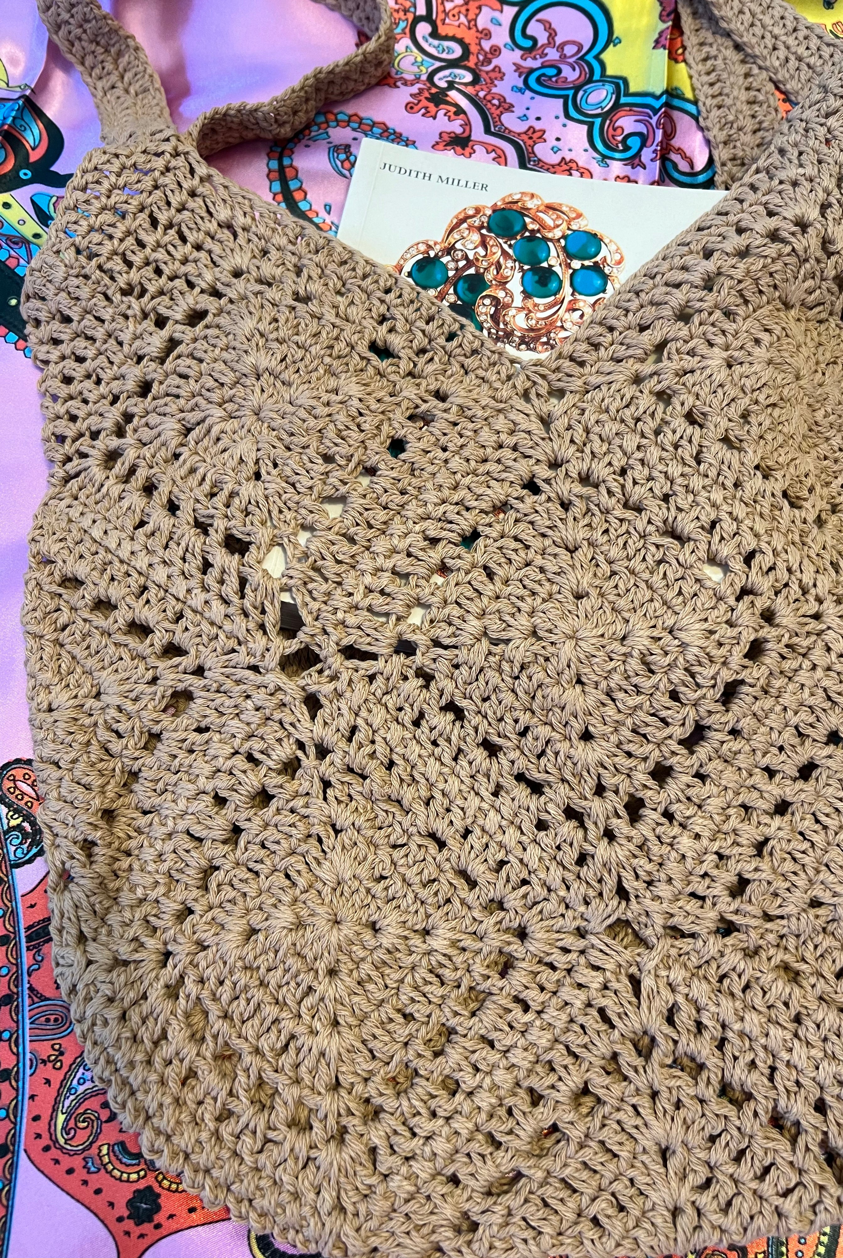 Tan crochet shoulder bag laid flat on a vibrant boho scarf background - artisan-style boho accessory Australia.