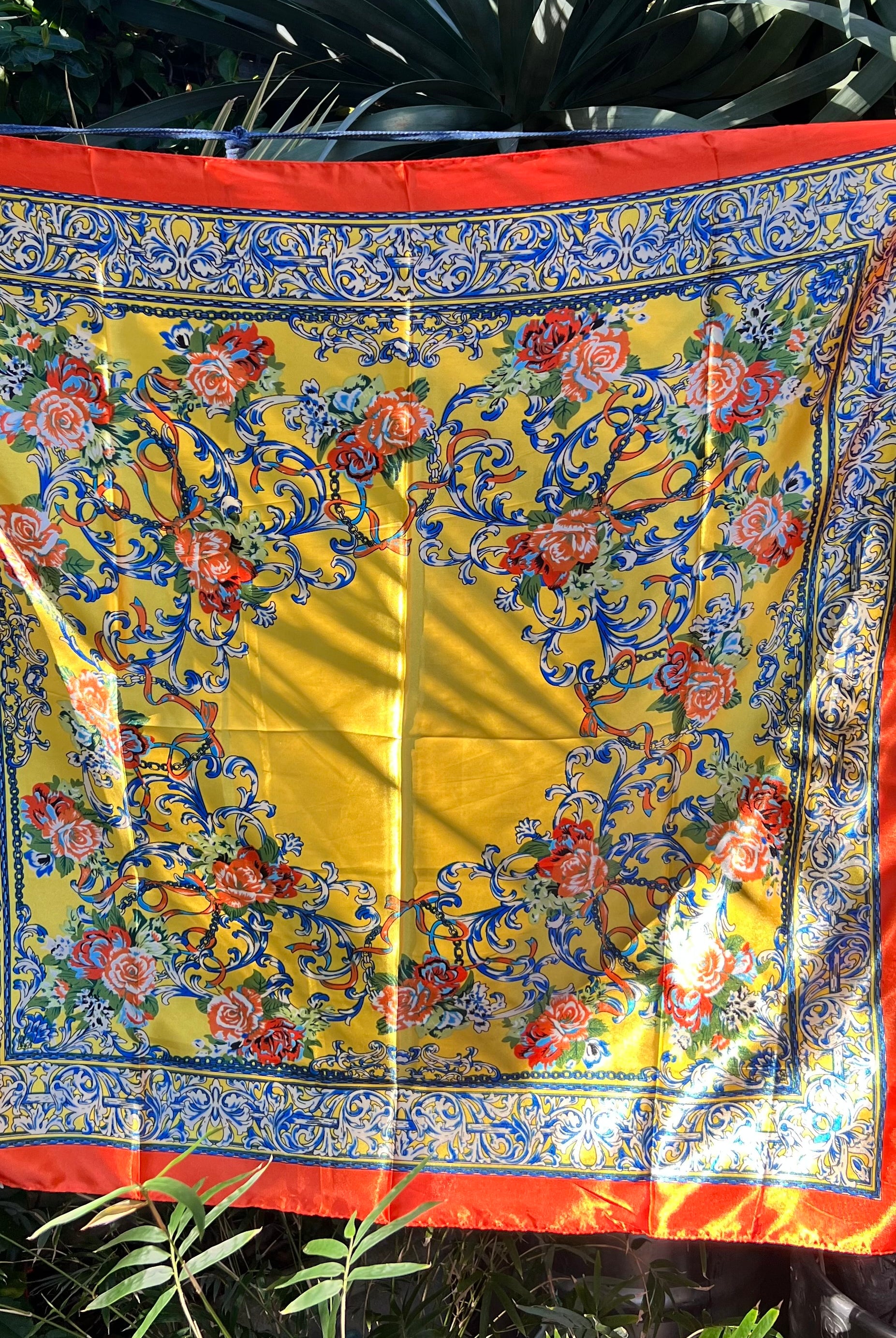 Yellow satin scarf with blue baroque scrolls and red floral print draped in sunlight - boho satin scarves Australia.