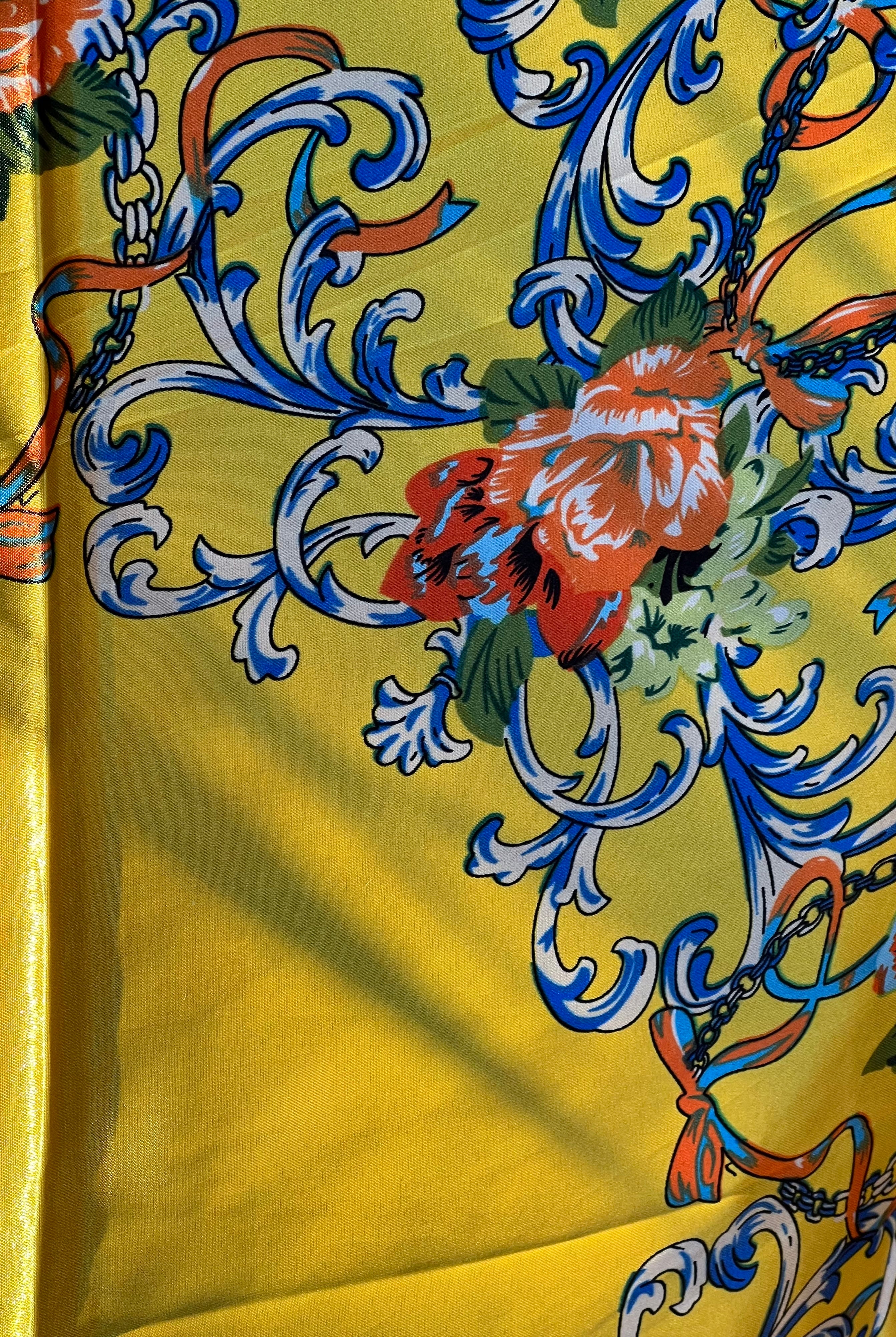 Yellow satin scarf with blue baroque scrolls and red floral print draped in sunlight - boho satin scarves Australia.