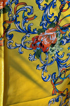 Yellow satin scarf with blue baroque scrolls and red floral print draped in sunlight - boho satin scarves Australia.