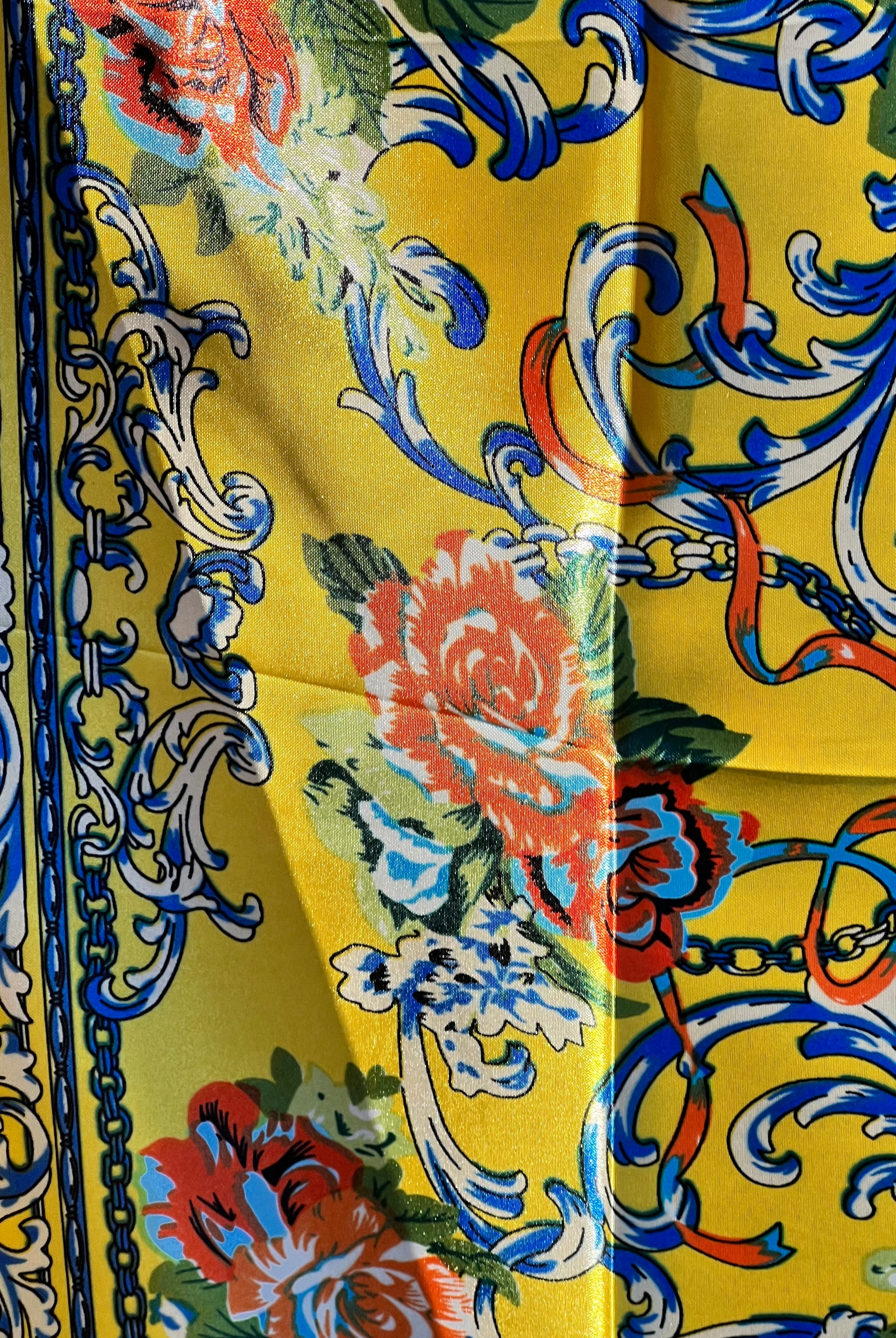 Yellow satin scarf with blue baroque scrolls and red floral print draped in sunlight - boho satin scarves Australia.