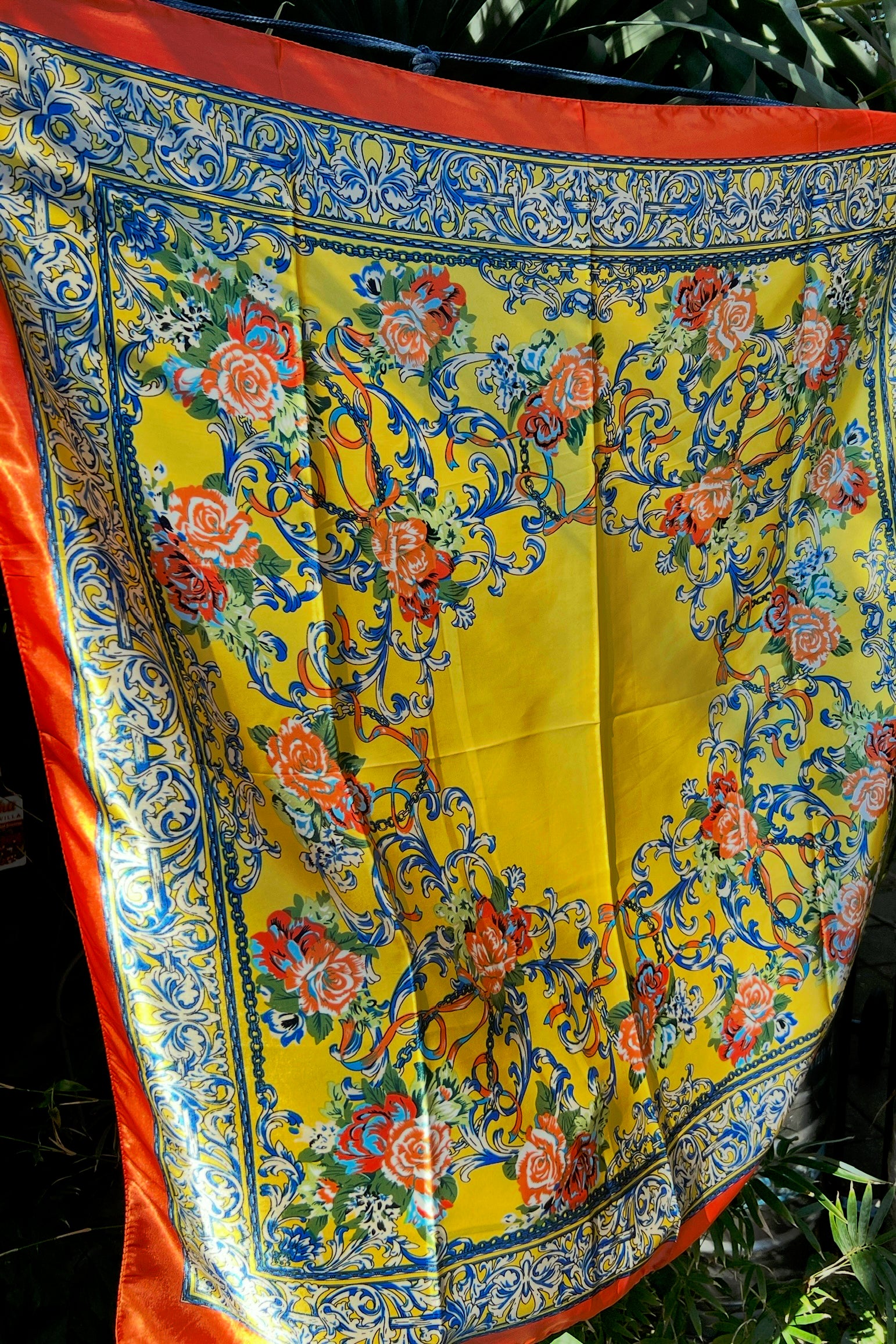 Yellow satin scarf with blue baroque scrolls and red floral print draped in sunlight - boho satin scarves Australia.