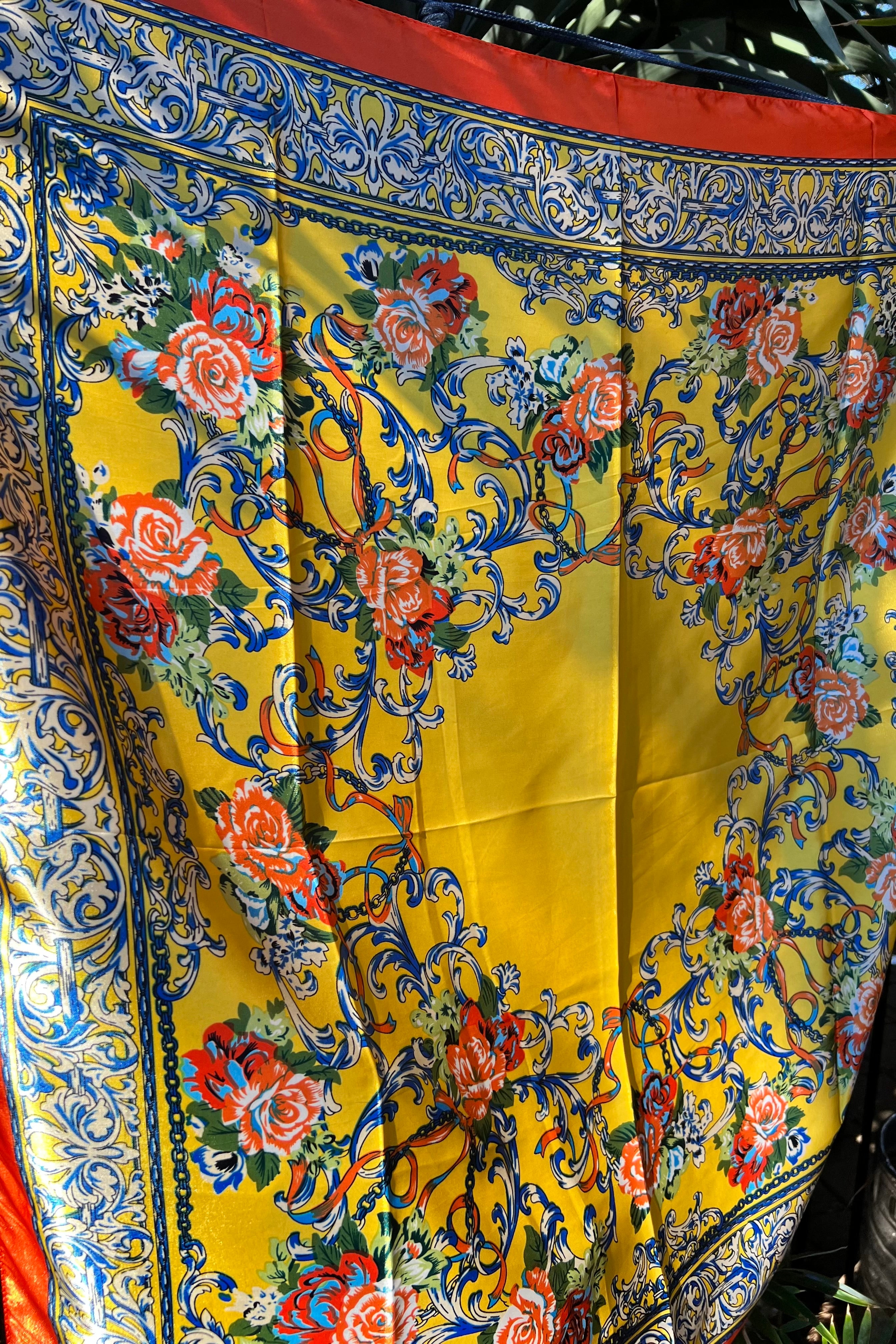Yellow satin scarf with blue baroque scrolls and red floral print draped in sunlight - boho satin scarves Australia.