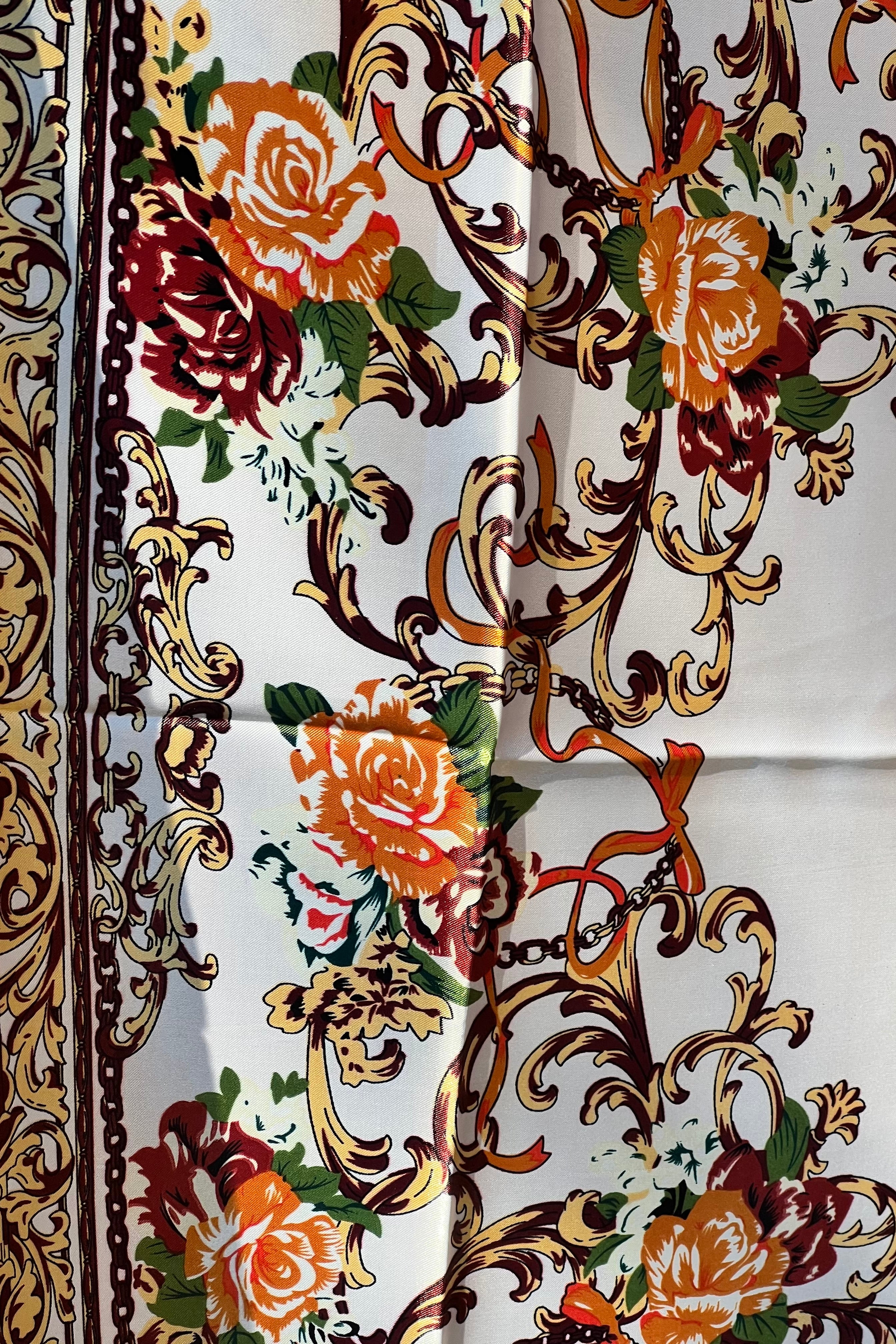 Brown satin square scarf with baroque floral print and red border in vintage-inspired warm tones.