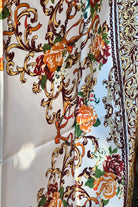Brown satin square scarf with baroque floral print and red border in vintage-inspired warm tones.