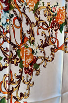 Brown satin square scarf with baroque floral print and red border in vintage-inspired warm tones.