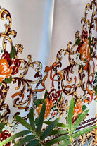 Brown satin square scarf with baroque floral print and red border in vintage-inspired warm tones.