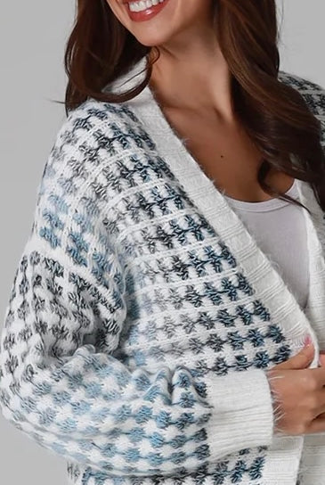 Woman wearing Juliet white and blue houndstooth longline fringe knit cardigan with drop shoulder sleeves, ribbed cuffs and front pockets by Charlotte The Label.
