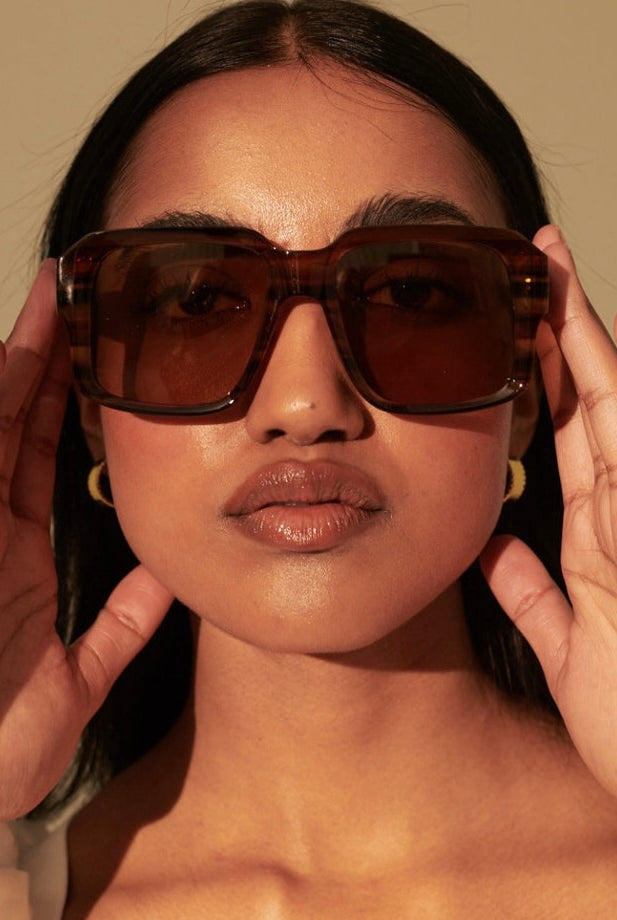 Woman in brown vintage square sunglasses with gold earrings and white shirt - tonal boho style Australia.