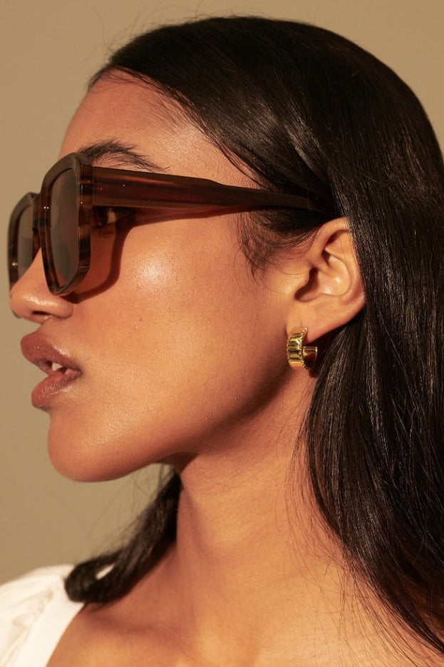 Woman in brown vintage square sunglasses with gold earrings and white shirt - tonal boho style Australia.