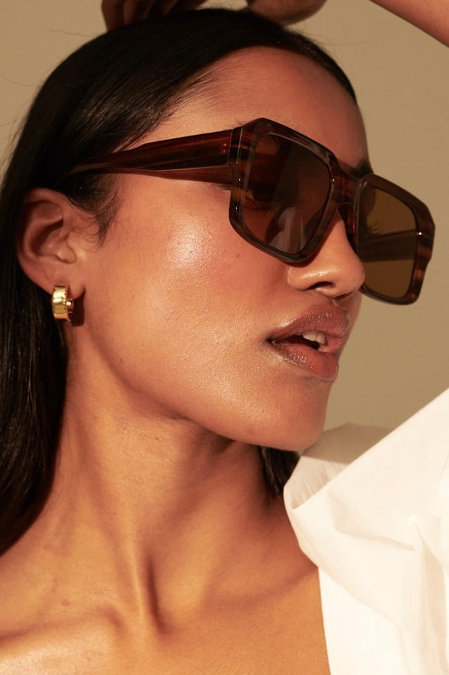 Woman in brown vintage square sunglasses with gold earrings and white shirt - tonal boho style Australia.