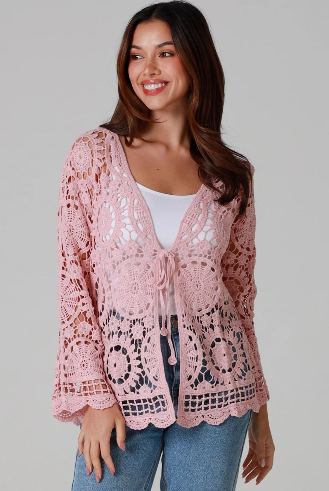 Women in blush pink cotton crochet cardigan with tie front and scalloped hem - boho chic cardigan Australia.