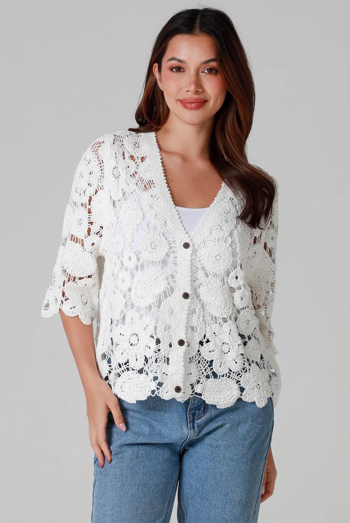 Woman wearing white floral crochet cardigan with scalloped hem - vintage-inspired boho knitwear Australia.