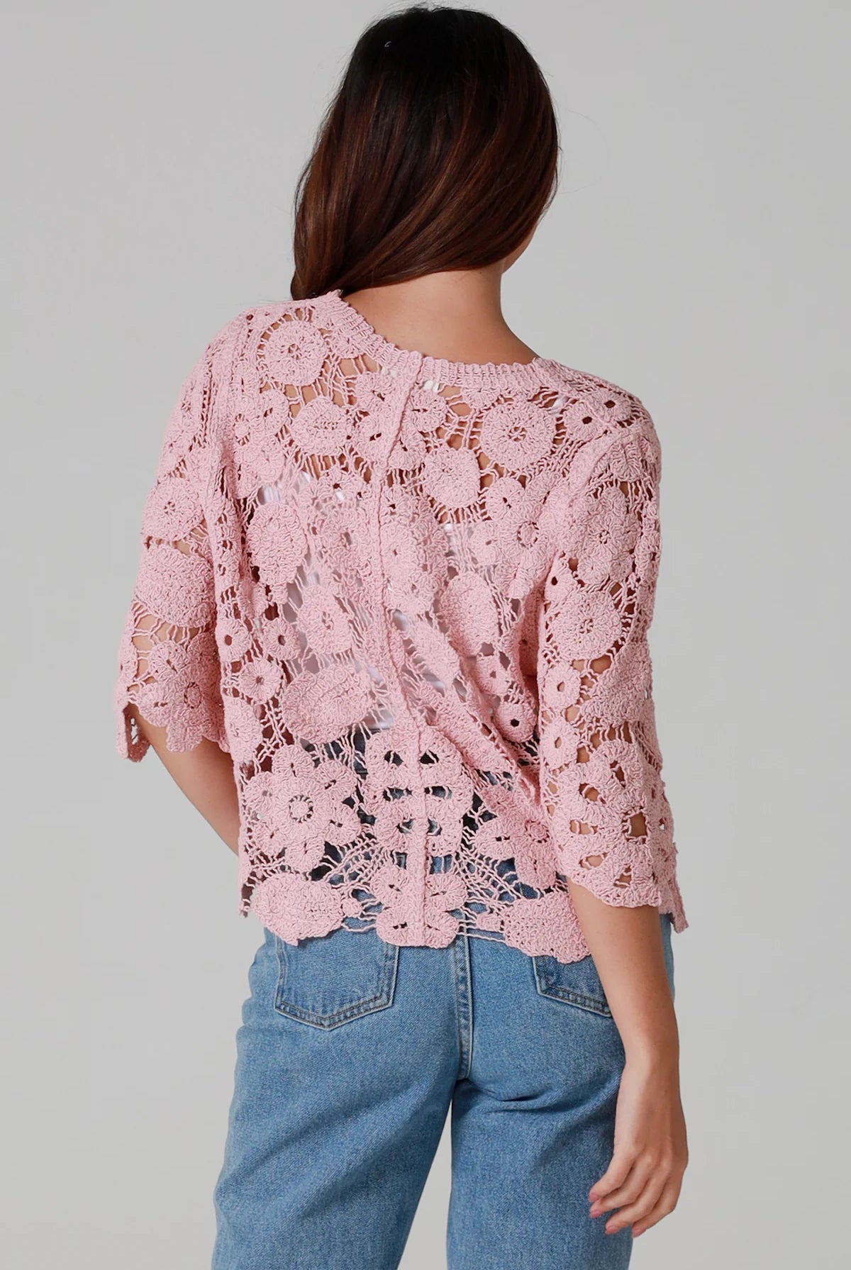 Woman in dusty rose pink floral crochet cardigan with scalloped hem - romantic boho knitwear Australia.