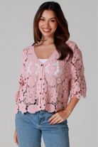 Woman in dusty rose pink floral crochet cardigan with scalloped hem - romantic boho knitwear Australia.