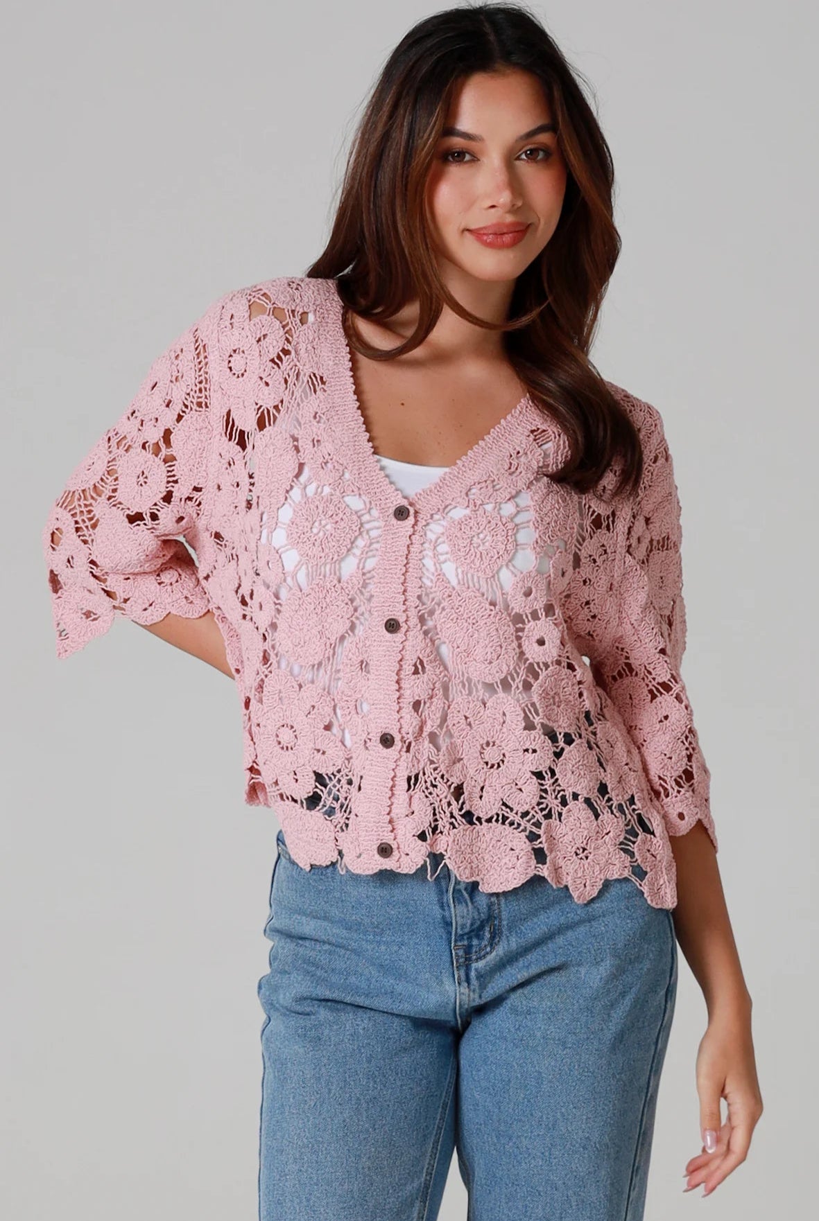 Woman in dusty rose pink floral crochet cardigan with scalloped hem - romantic boho knitwear Australia.