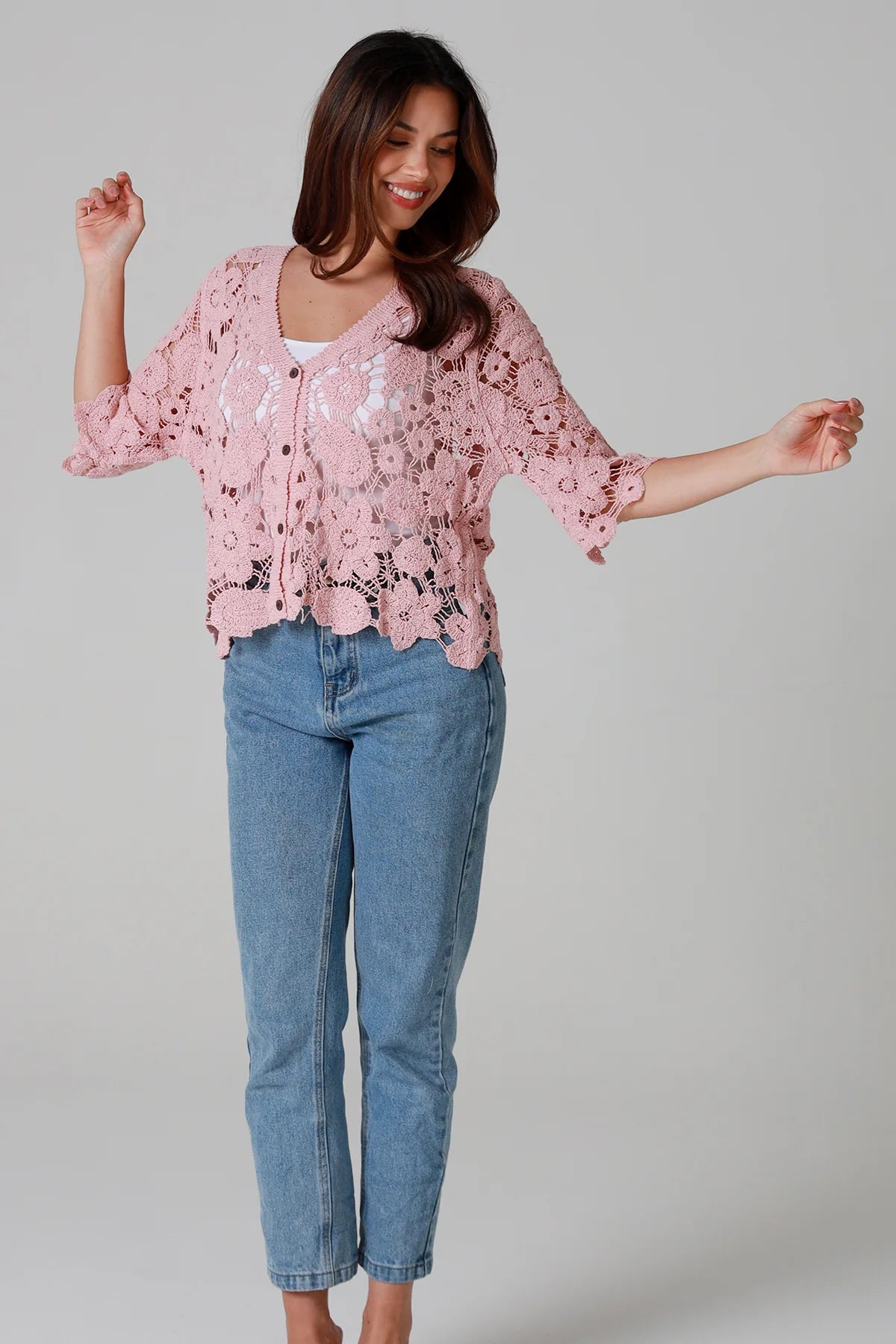 Woman in dusty rose pink floral crochet cardigan with scalloped hem - romantic boho knitwear Australia.