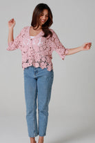 Woman in dusty rose pink floral crochet cardigan with scalloped hem - romantic boho knitwear Australia.