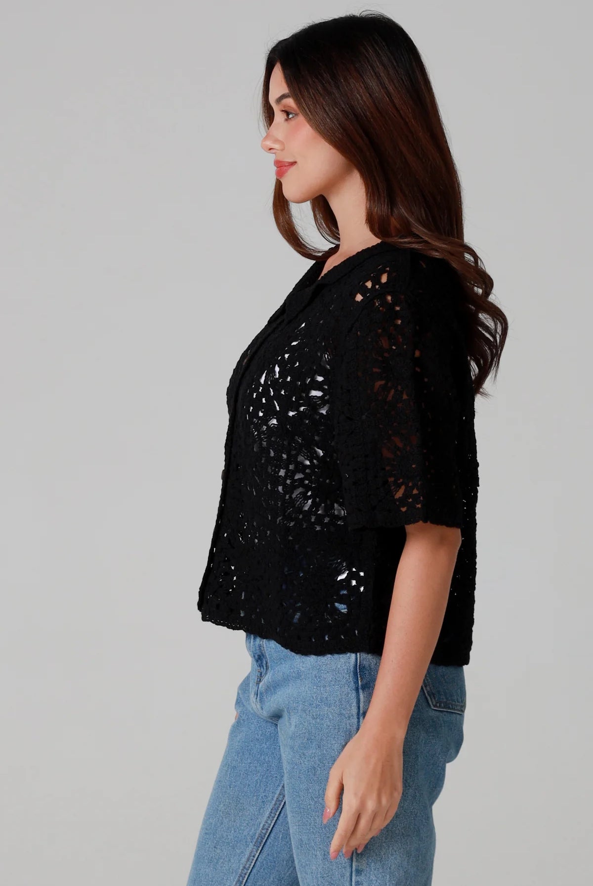 Woman wearing a black cotton crochet cardigan with collar and short sleeves styles with light blue jeans - boho crochet top Australia.
