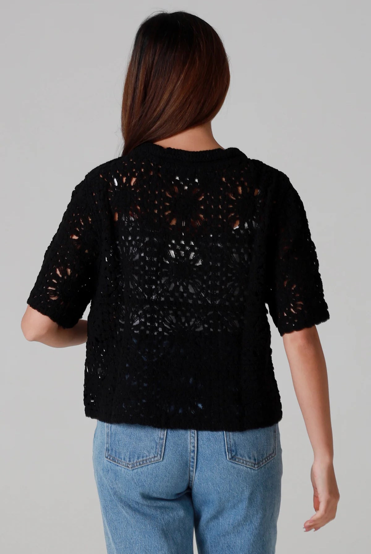 Woman wearing a black cotton crochet cardigan with collar and short sleeves styles with light blue jeans - boho crochet top Australia.