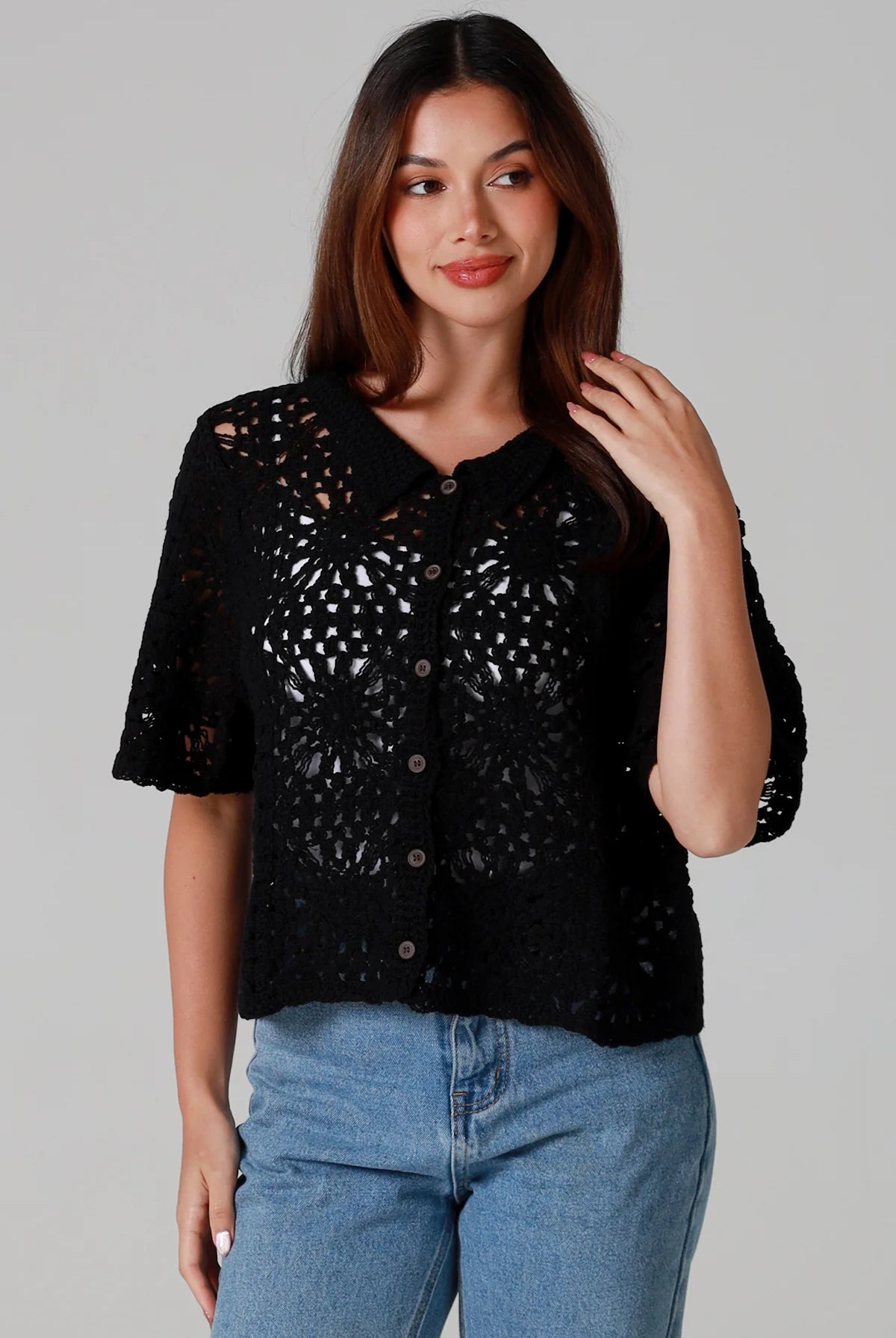 Woman wearing a black cotton crochet cardigan with collar and short sleeves styles with light blue jeans - boho crochet top Australia.