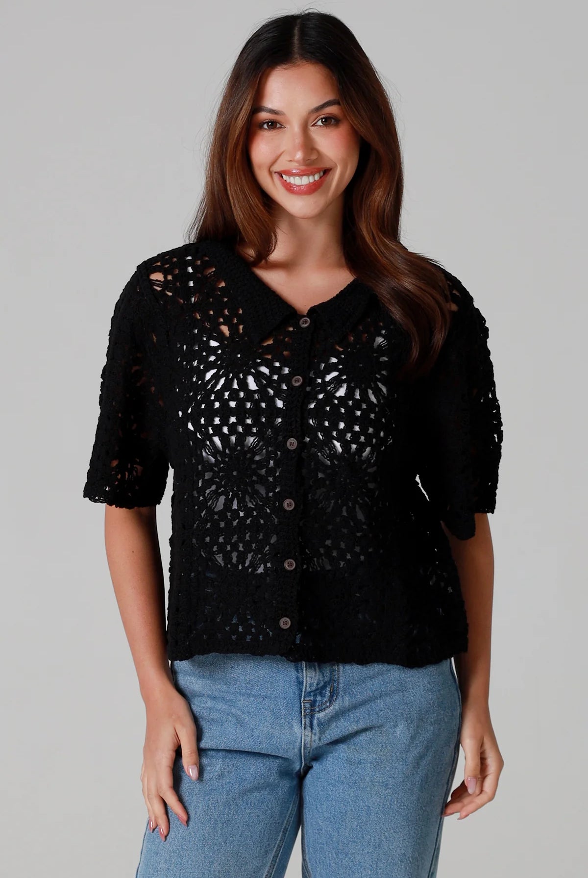 Woman wearing a black cotton crochet cardigan with collar and short sleeves styles with light blue jeans - boho crochet top Australia.