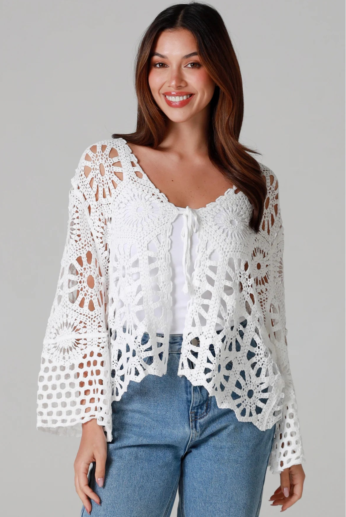 White crochet cardigan with tie front and boho bell sleeves layered over denim - crochet cardigan Australia.