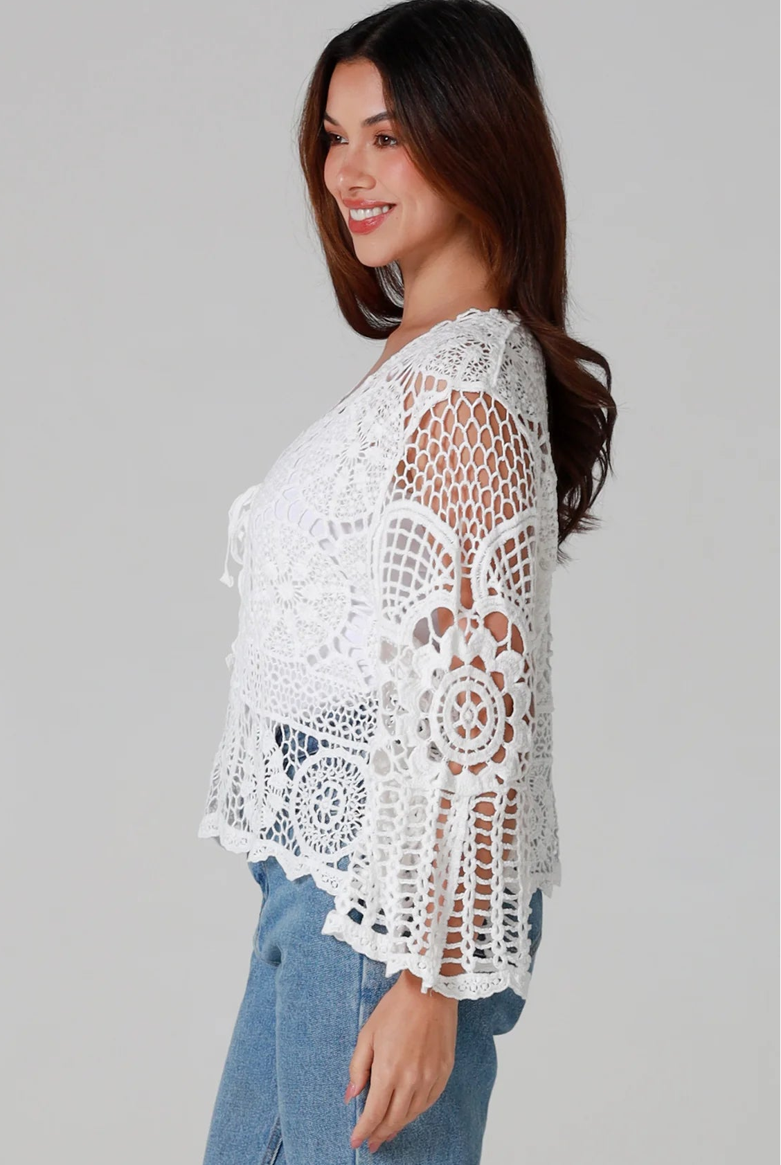 Woman in white cotton crochet embroidered top with flared sleeves and tie-front – Australian boho style
