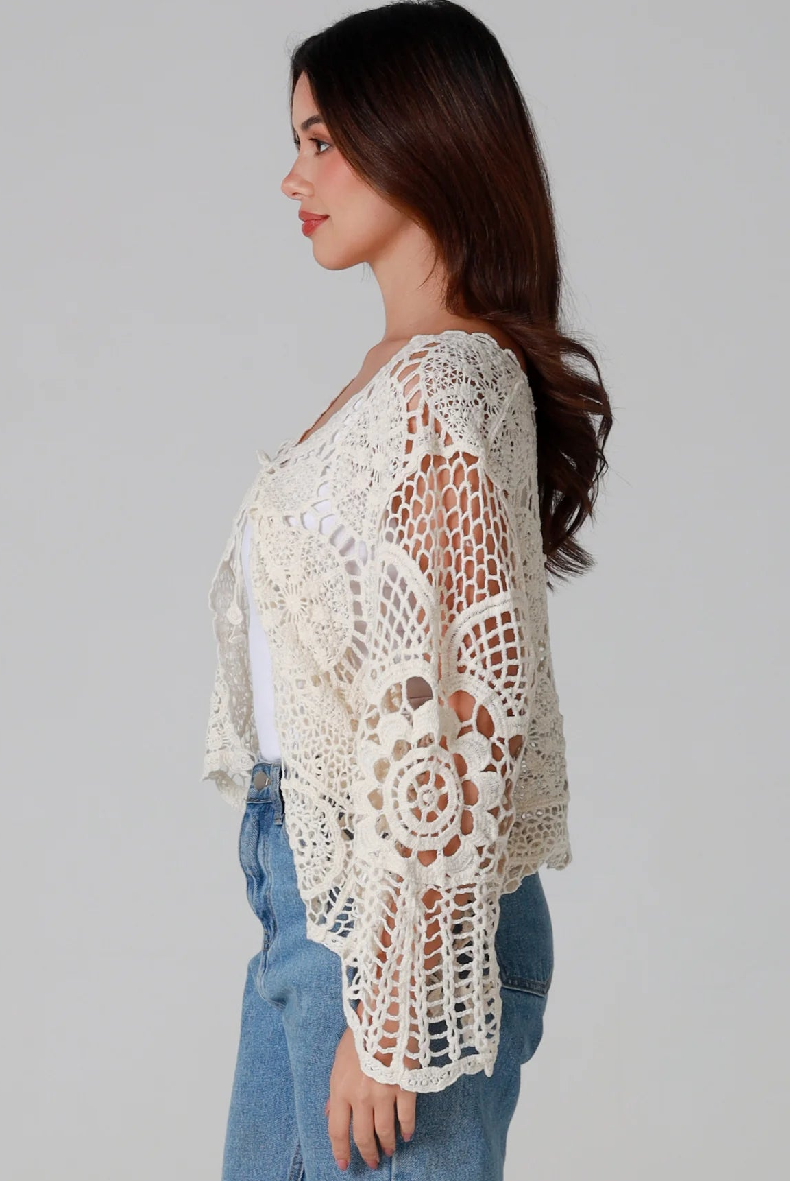 Woman in cream cotton crochet embroidered cardigan with flared sleeves and scalloped edges – Australian boho style
