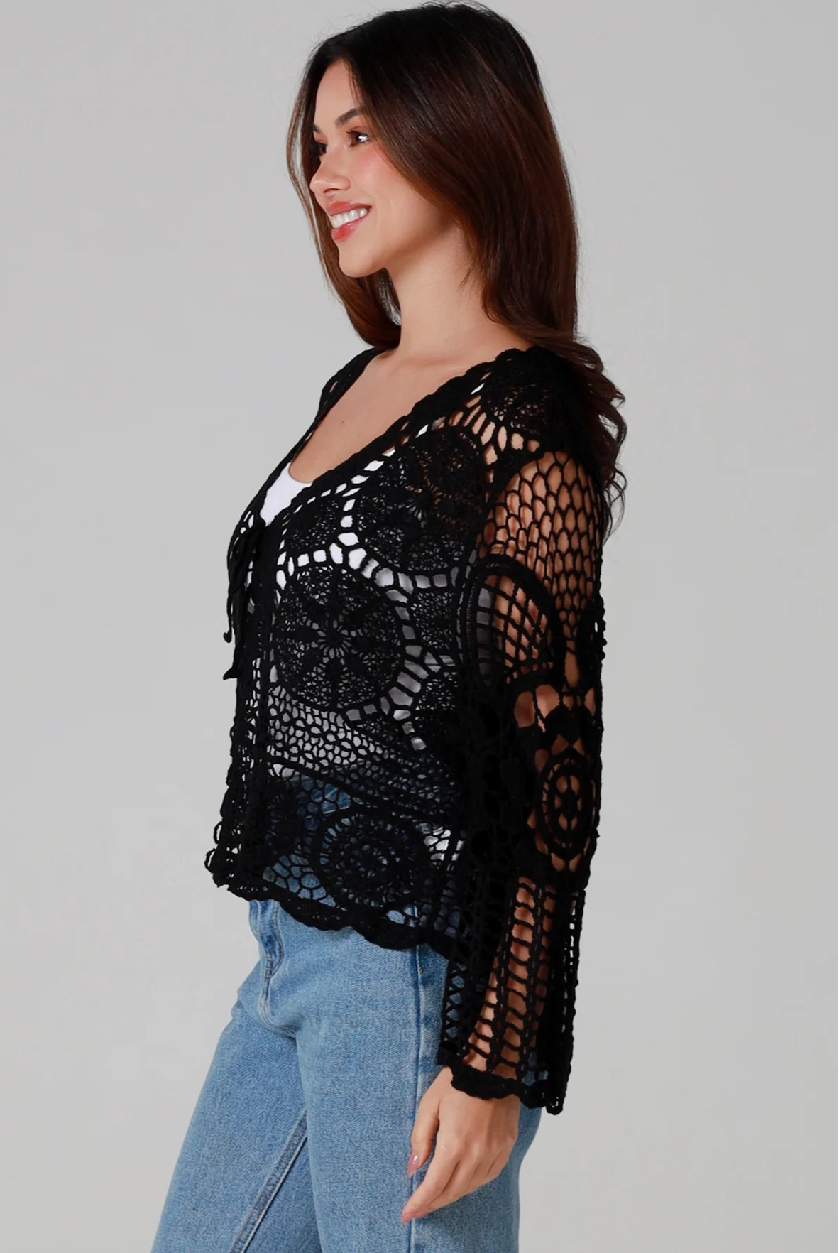Woman in black 100% cotton crochet top with bell sleeves and tie front - one size boho top styled with denim