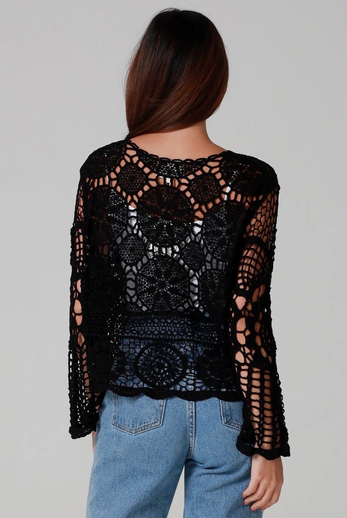 Woman in black 100% cotton crochet top with bell sleeves and tie front - one size boho top styled with denim