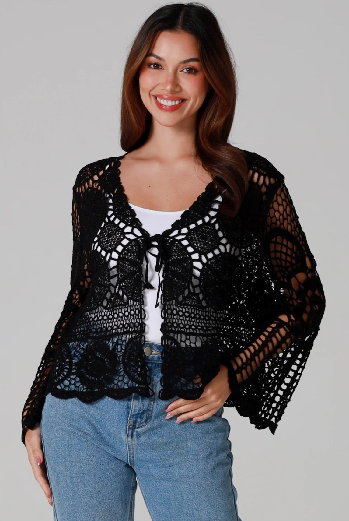 Woman in black 100% cotton crochet top with bell sleeves and tie front - one size boho top styled with denim