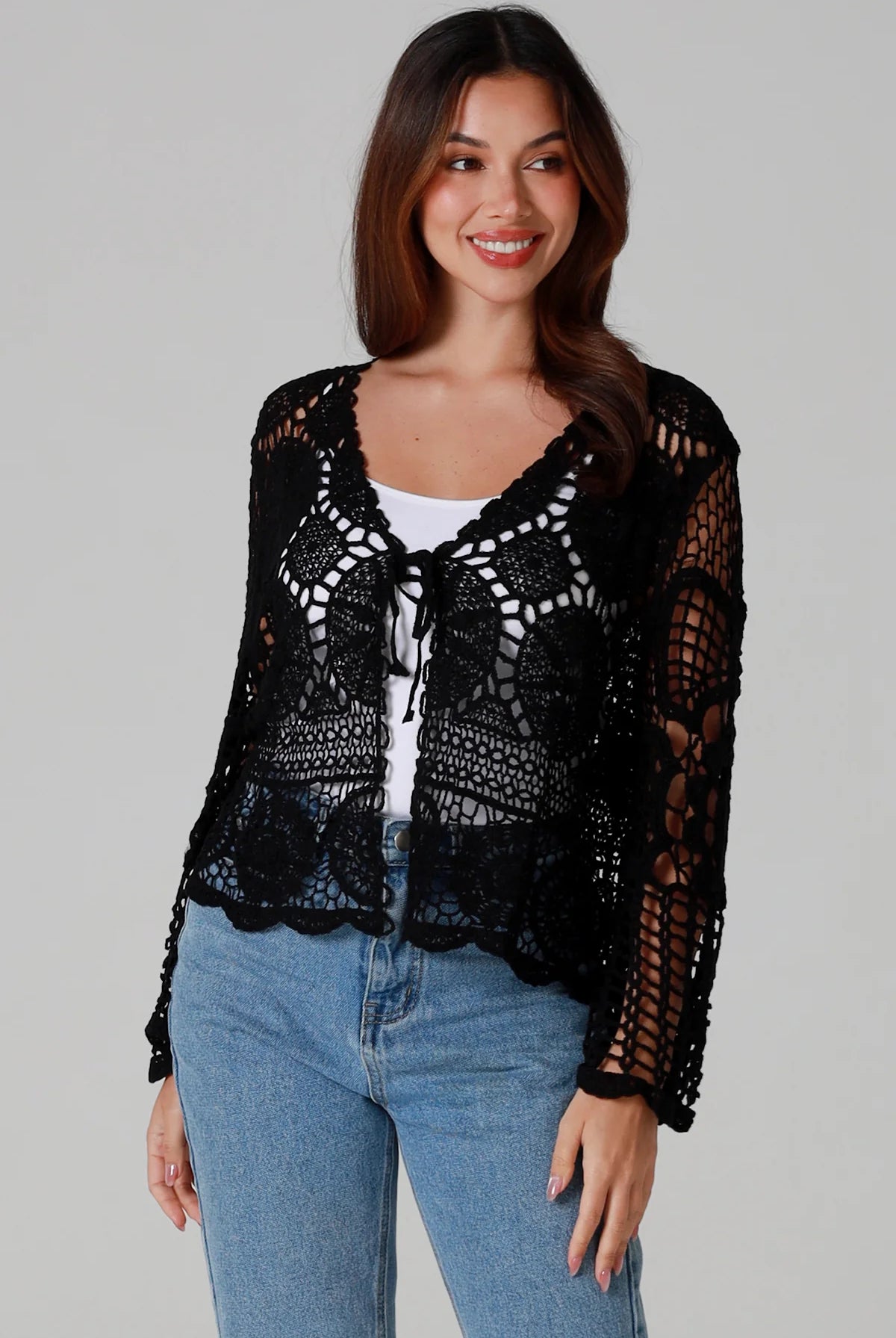Woman in black 100% cotton crochet top with bell sleeves and tie front - one size boho top styled with denim