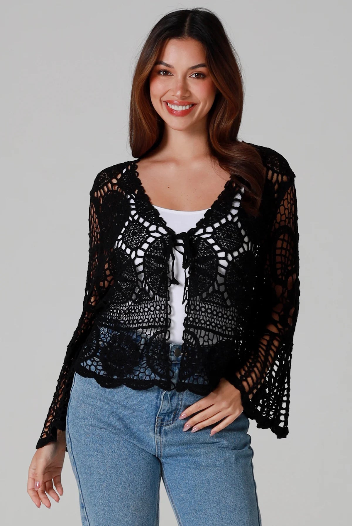 Woman in black 100% cotton crochet top with bell sleeves and tie front - one size boho top styled with denim