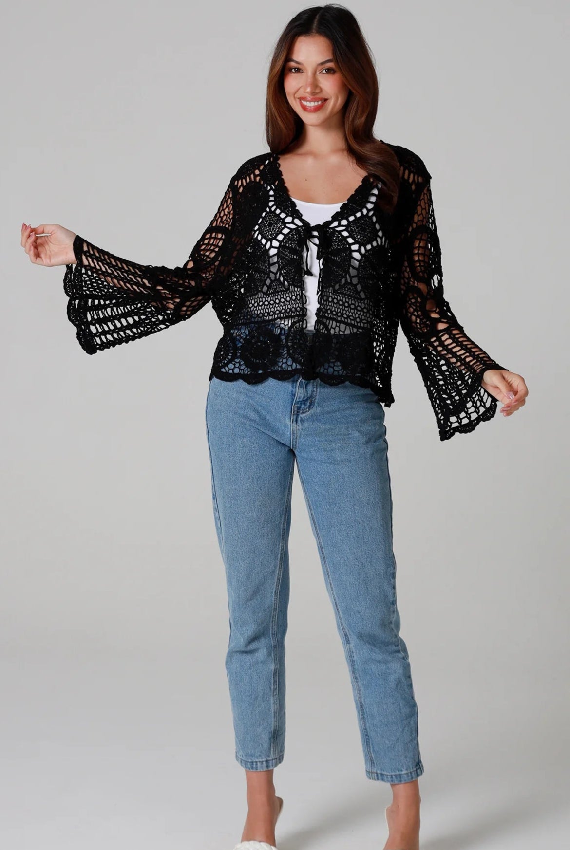 Woman in black 100% cotton crochet top with bell sleeves and tie front - one size boho top styled with denim