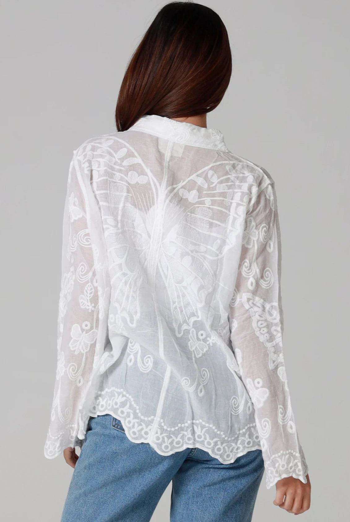Woman in white cotton embroidered butterfly shirt with scalloped cuffs - boho blouse Australia.