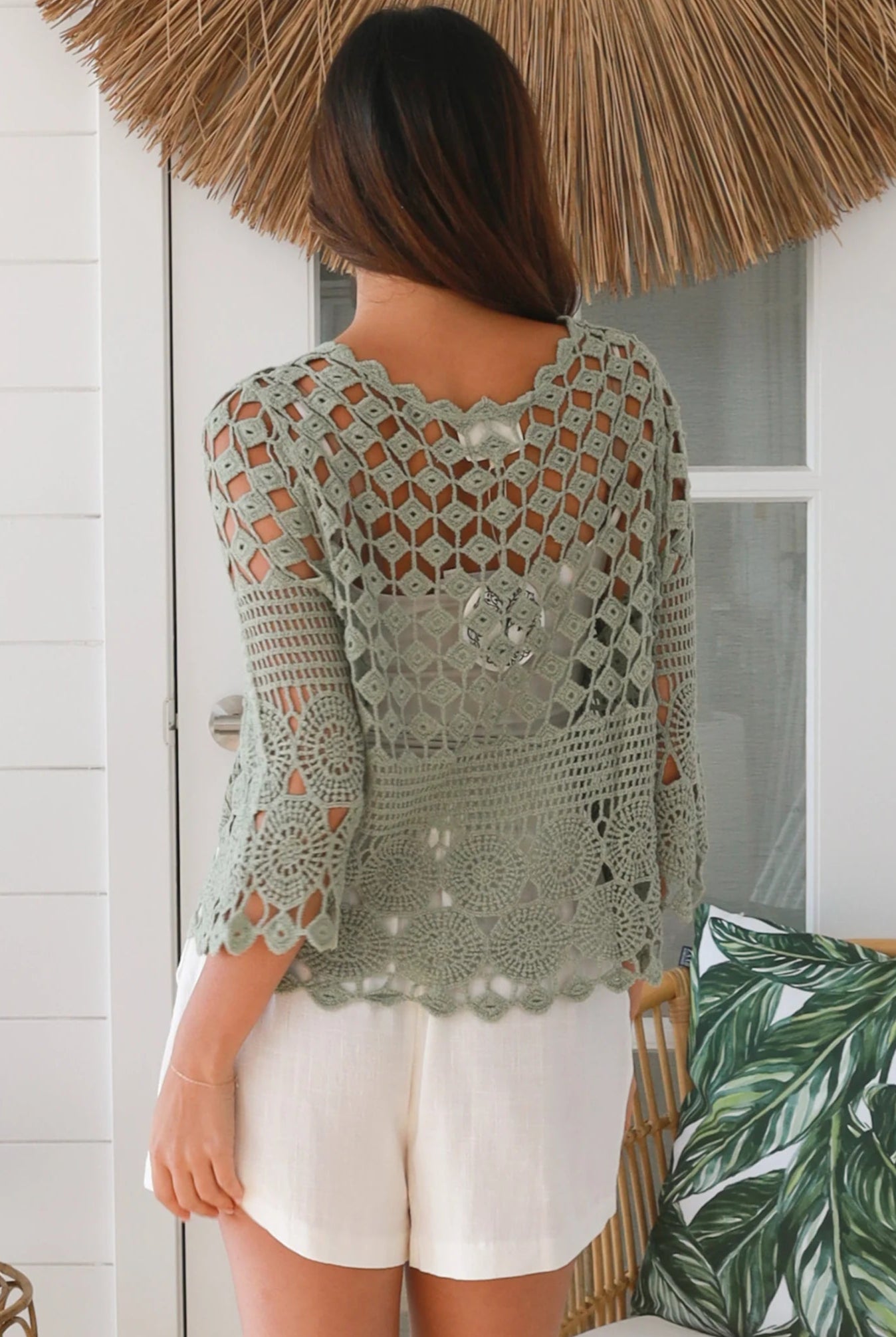 Woman wearing a sage green crochet cotton cardigan with floral and diamond pattern and scalloped sleeves - boho fashion Australia