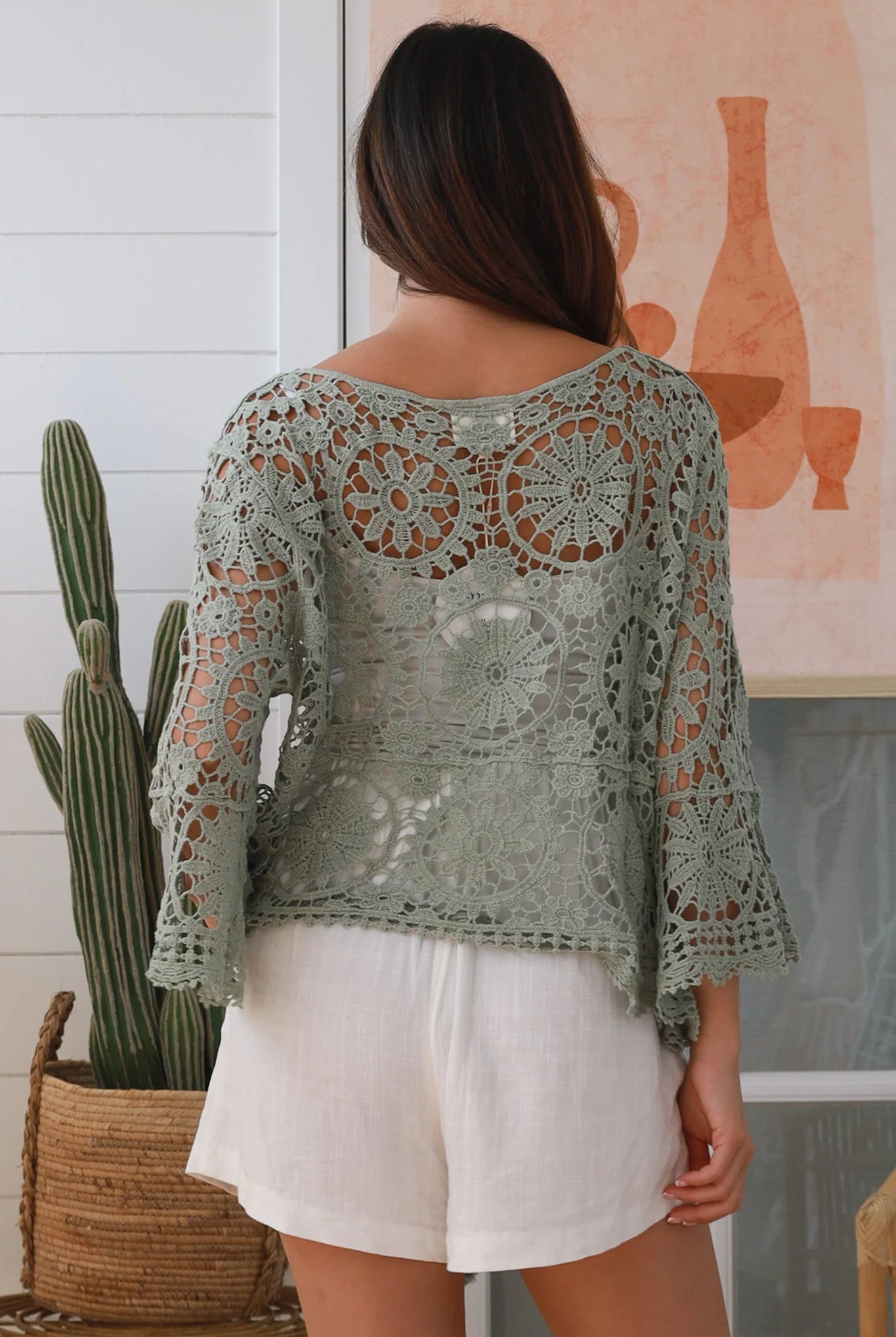 Woman wearing sage crochet boho top with dramatic bell sleeves - festival fashion Australia.